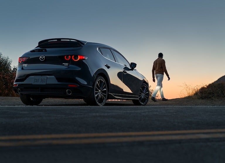 man walking in front of his car at dusk from Fitzgerald Mazda Frederick in Frederick MD 